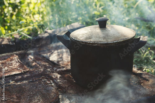 Cooking dinner in old camping kettle on picnic. Closeup.