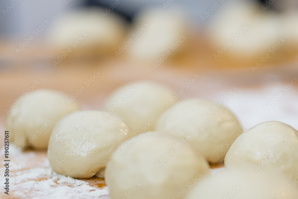 Closeup of ball ready dough on floured kitchen table. Defokus in the background.