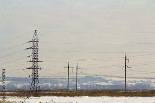 High power powerline poles with high voltage cables through the field photo