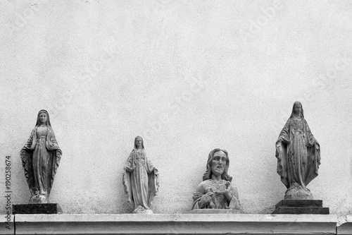 Black and white photo. Statues of Jesus and the Virgin Mary on a wall background