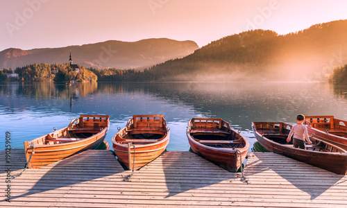 Wooden boats on the lake Bled at sunset.  In the background is the famous catholic church on the spectacular island. Bled, Slovenia, Europe at autumn sunset