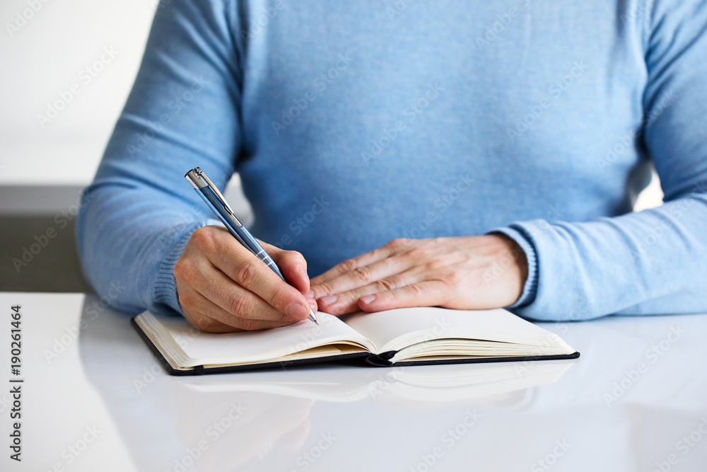 A man writes a black diary close up A man writes a black diary close up