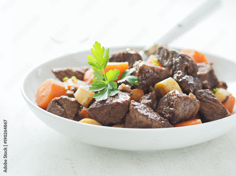Beef meat stewed with carrots  in white plate.