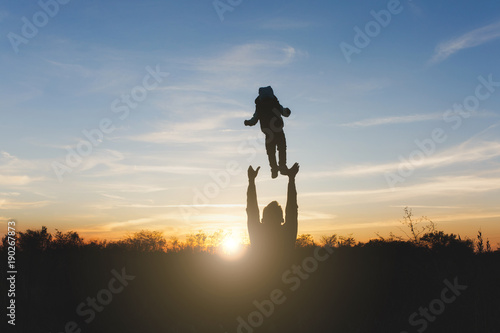 Silhouette of man high toss up little cute child baby boy on nature, sunset horizon background. Father throw up fun little kid son outdoors. Family day 15 of may, love, parents, children concept. © ViDi Studio