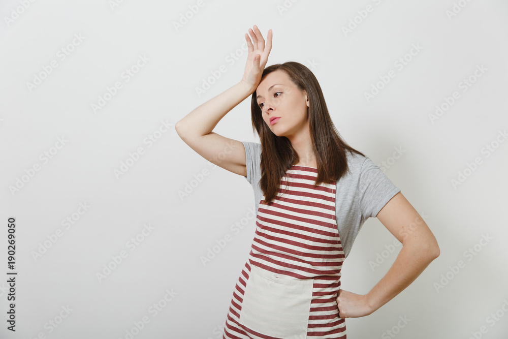 Young attractive sad upset tired brunette caucasian housewife in striped apron isolated on white background. Beautiful housekeeper woman put and touch her hand to head. Copy space for advertisement. Young attractive sad upset tired brunette caucasian housewife in striped apron isolated on white background. Beautiful housekeeper woman put and touch her hand to head. Copy space for advertisement.
