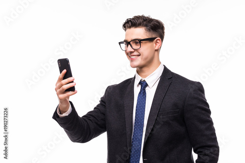 Great news. Handsome young man using his phone with smile while standing against white background. photo