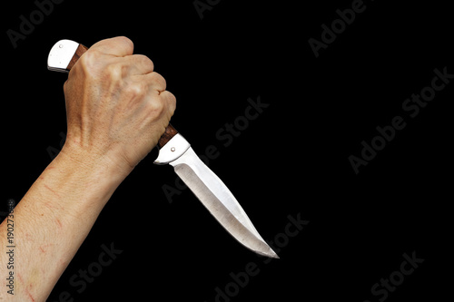 Human hand holding knife isolated on black. Copyspace.