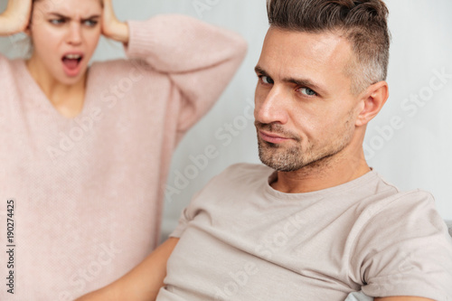 Close-up image of Confused man sitting on couch with girlfriend