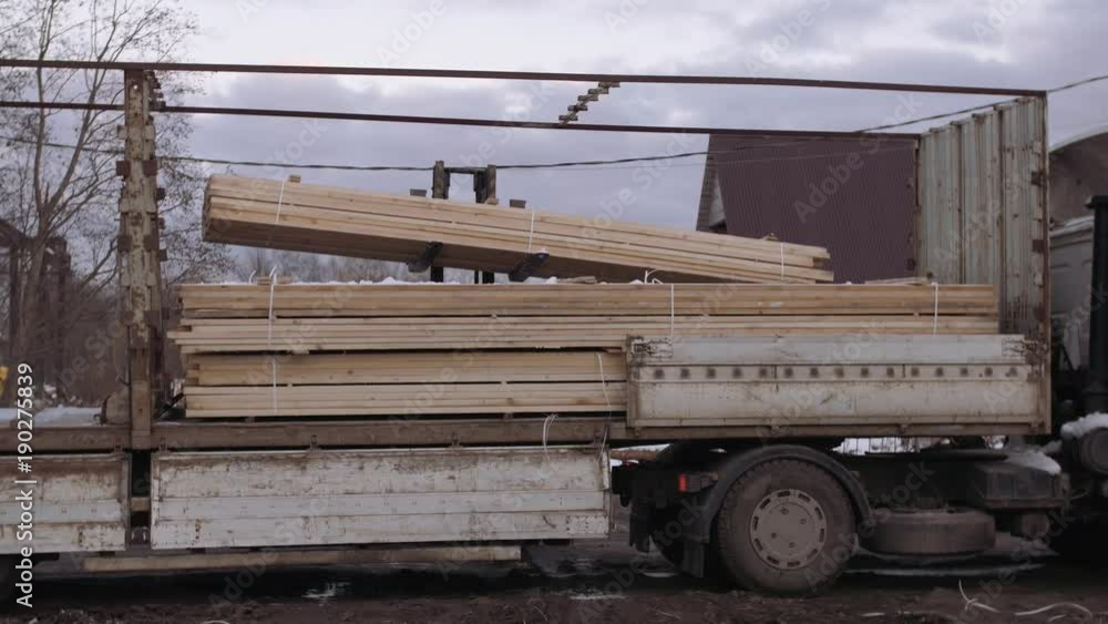 Forklift uploads heavy truck with wood block stacks at woodwork facility on cold winter day at dirty road Forklift uploads heavy truck with wood block stacks at woodwork facility on cold winter day at dirty road