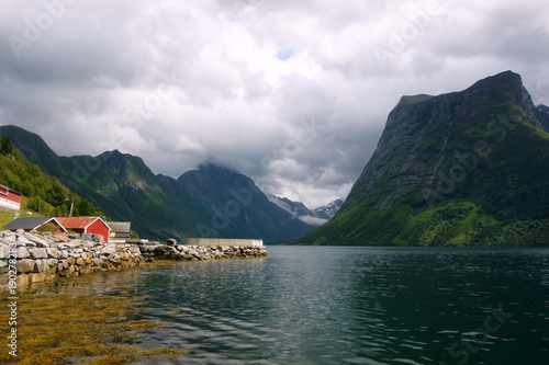 Picturesque scene of Urke village and Hjorundfjorden fjord, Norway. Drammatic sky and gloomy mountains panorama © Ivan Kmit