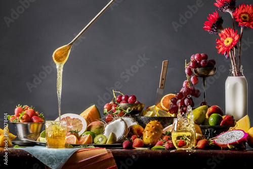Fruit and honey still life with strawberry splashing in champagne glass. 