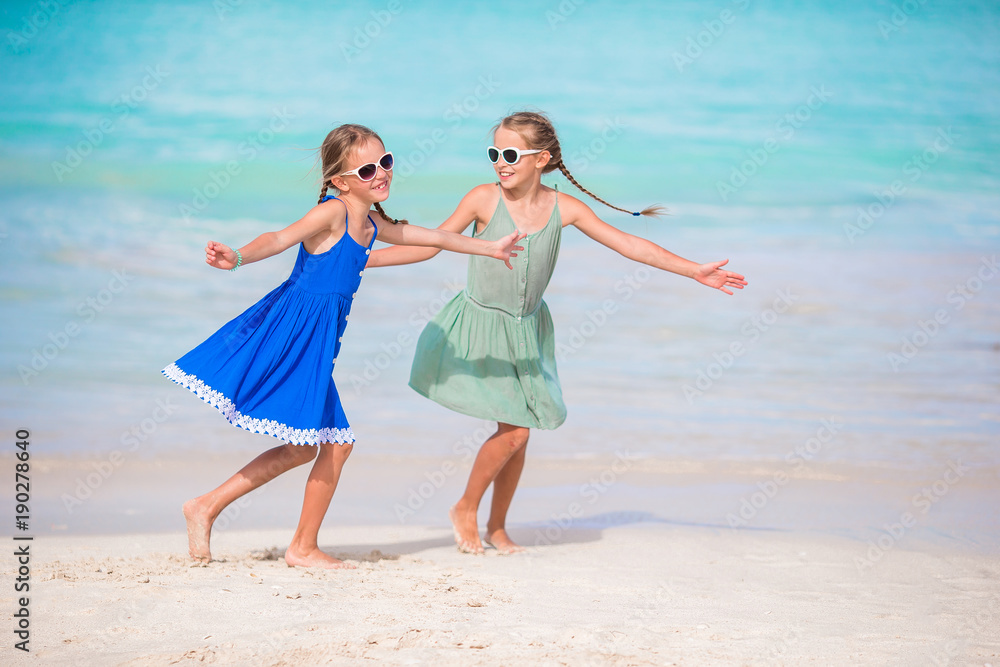 Adorable little girls have a lot of fun on the beach. Two beautiful kids are happpy