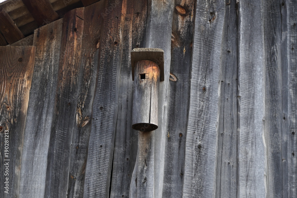 wooden birdhouse on the wall of a wooden barn