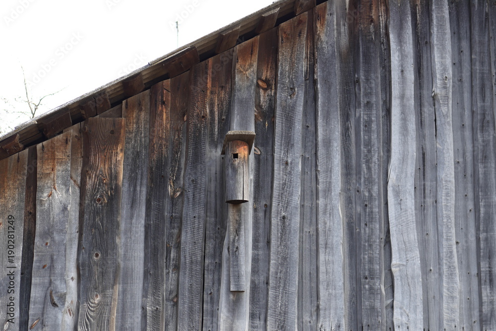 wooden birdhouse on the wall of a wooden barn