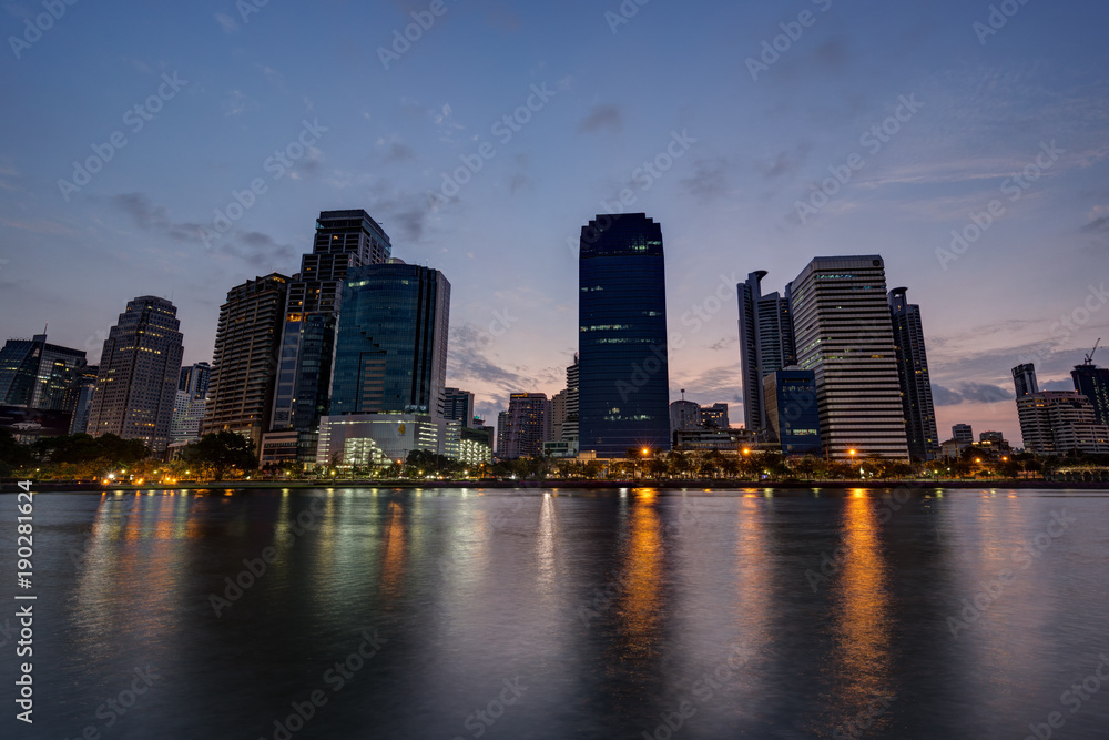 View of modern skyscrapers behind a lake at the Benjakiti (Benjakitti) Park in Bangkok, Thailand, at dawn.