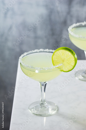 Margarita, Tequila Cocktail Straight Up with Salted Rim and Lime Wedge on Marble Counter