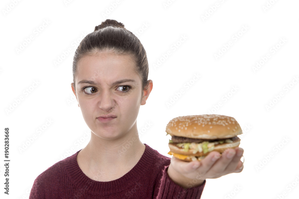 Adolescent girl looking suspiciously at a hamburger on a white background