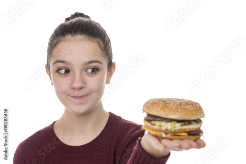 Adolescent girl enjoying a hamburger on a white background