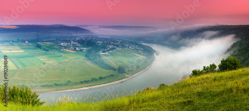 Panoramic view from the hill on bend of the river. Beautiful summer landscape. Colorful pink sky of the morning. Dniester Canyon located at the territory of Dniester River Valley in Ukraine. photo