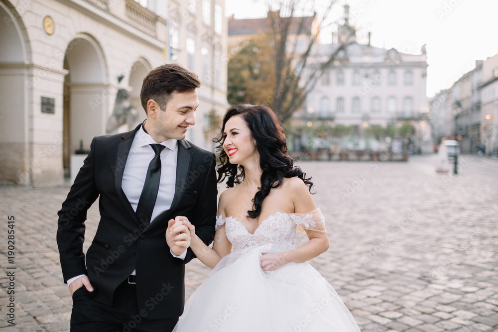 Naklejka premium Bride and groom walking through the old town