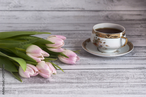 Bukiet różowych tulipanów na drewnianym stole z porcelanową filiżanką herbaty