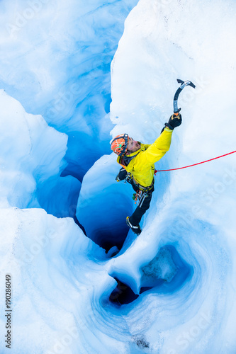 Ice climber on rope climbing out of moulin with multiple vertical tunnels photo