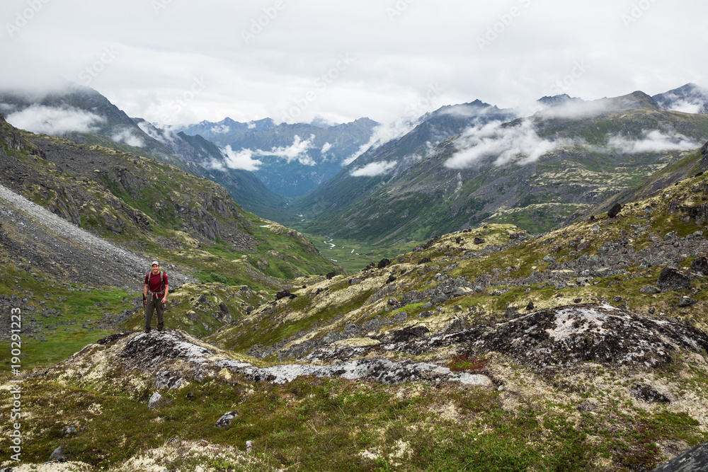 Hiker standing above glacial valley in Talkeetna Mountains, Alaska