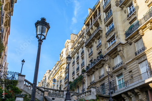 Tableau sur toile Low angle view of opulent-looking, Haussmannian style buildings in the chic neighborhoods of Paris, with period street lights in the foreground against blue sky