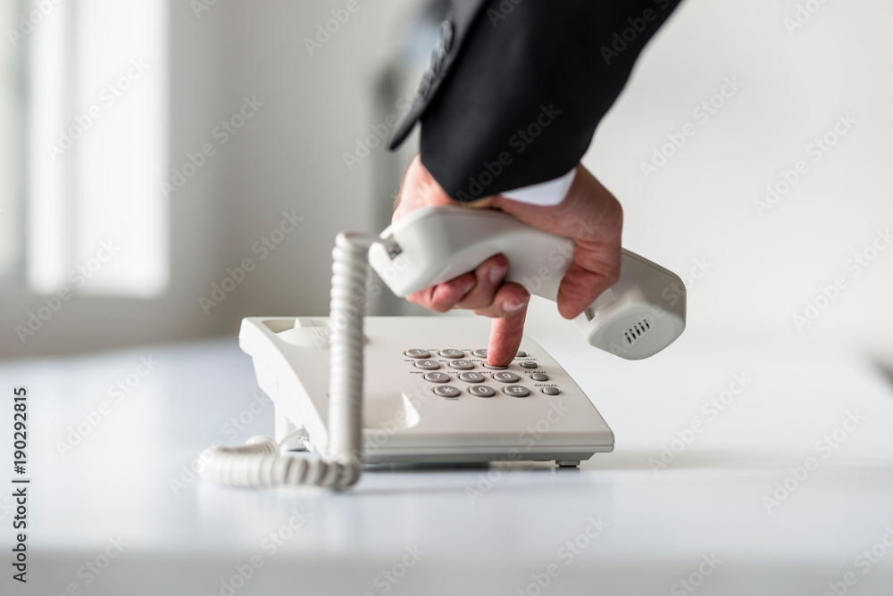 Male hand dialing a telephone number in order to make a phone call - obrazy, fototapety, plakaty 