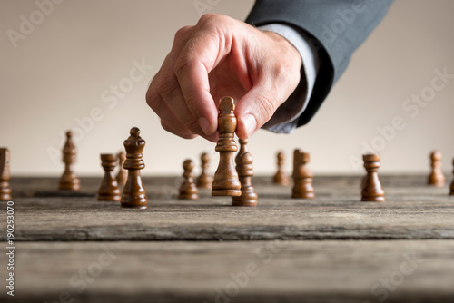 Human hand wearing business suit moving dark King chess piece photo