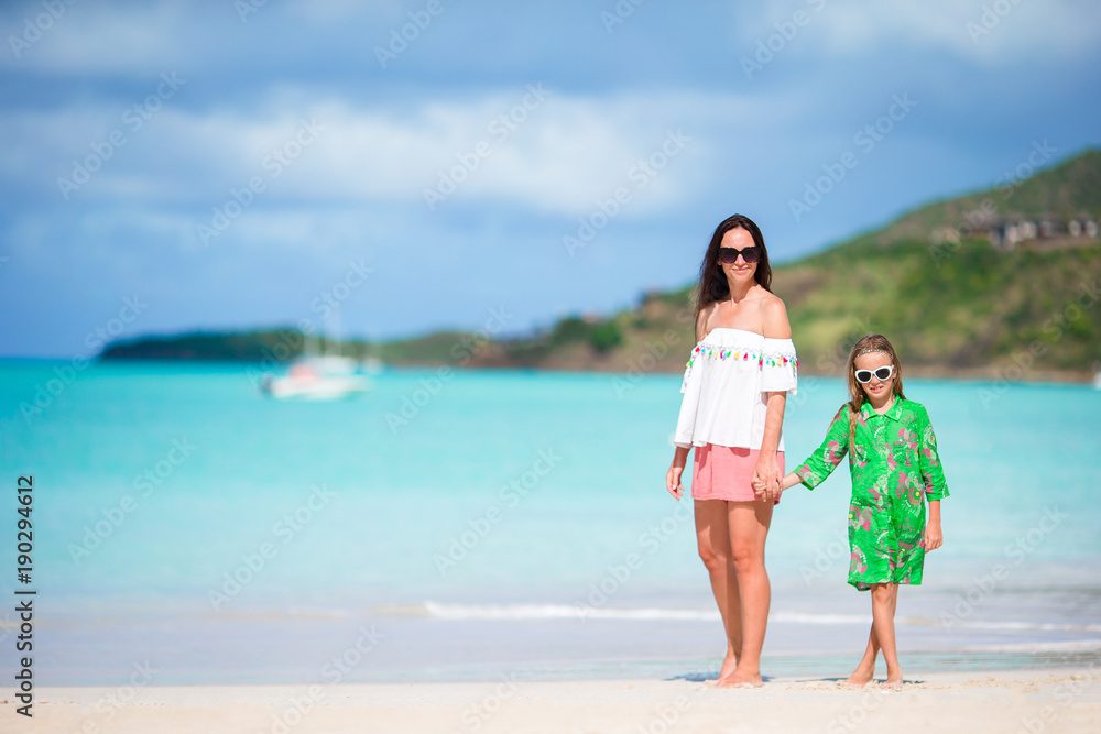 Beautiful mother and daughter at Caribbean beach enjoying summer vacation
