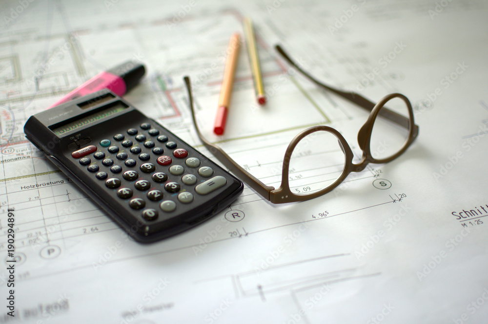 Architectural drawing on a table with glasses, calculator, pencil, marker and pen. Architectural drawing on a table with glasses, calculator, pencil, marker and pen.