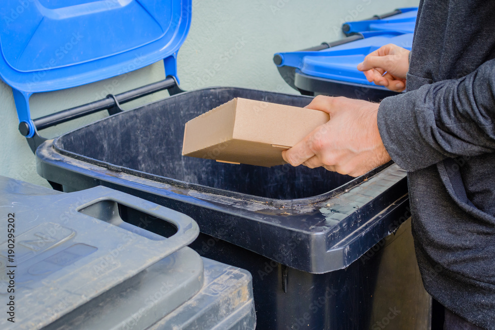 Men putting card paper box in blue garbage container Men putting card paper box in blue garbage container