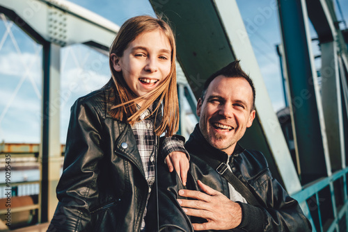 Father and daughter sitting on the bridge and laughing