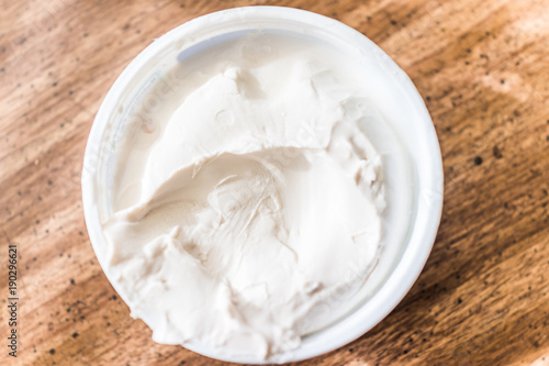 Vászonkép Closeup of small tub plastic container of white cream cheese on table, flat top