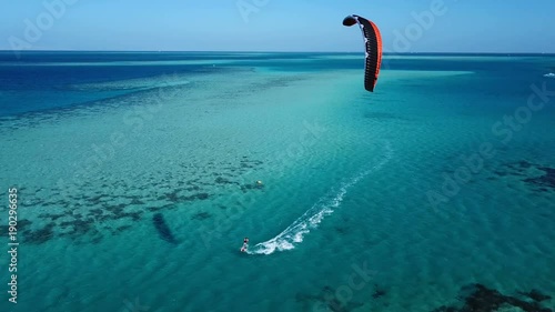 Aerial view young man kite surfing in tropical blue ocean