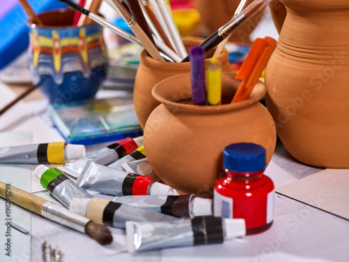Authentic paint brushes still life on table in art class school as drawing course. Group of brush in clay jar.