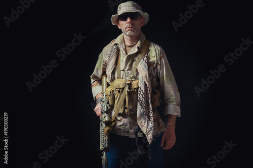 soldier of the American special forces in Afghanistan poses with a rifle on a black background