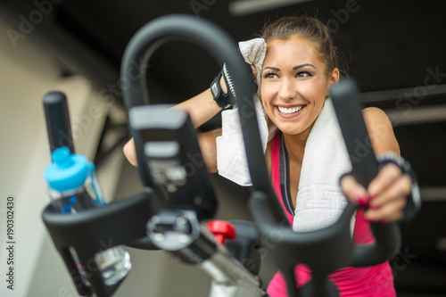 Beautiful young woman doing cardio on a stationary bike photo