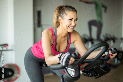 Beautiful young woman doing cardio on a stationary bike