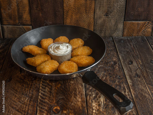 Freshly cooked nuggets in a frying pan with sauce