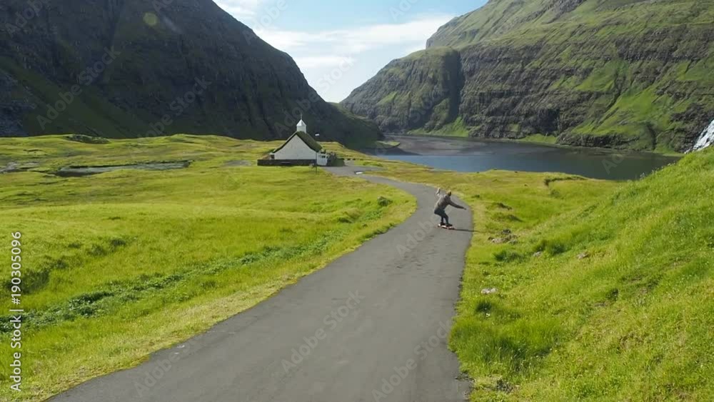 A young man Longboard Skateboarding down hill in rural Faroe Islands Denmark A young man Longboard Skateboarding down hill in rural Faroe Islands Denmark