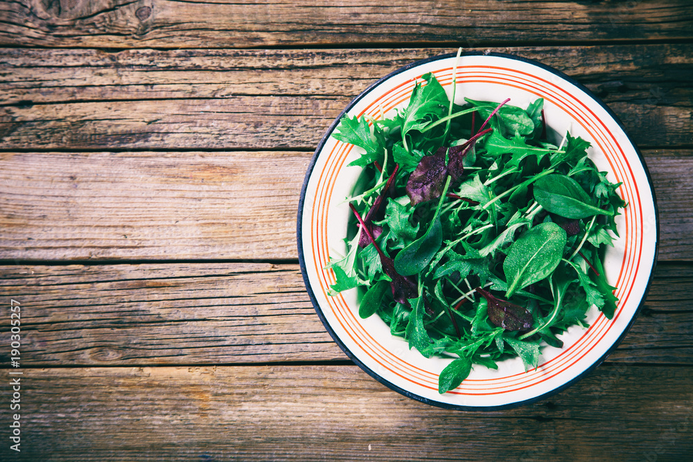 Fresh Green Mix Salad on Wooden background.Leaves Of Spinach,Arugula,Romaine,Lettuce.Concept of Healthy Food.Vegetarian.Copy space for Text. selective focus.Toned image.Vintage style Fresh Green Mix Salad on Wooden background.Leaves Of Spinach,Arugula,Romaine,Lettuce.Concept of Healthy Food.Vegetarian.Copy space for Text. selective focus.Toned image.Vintage style