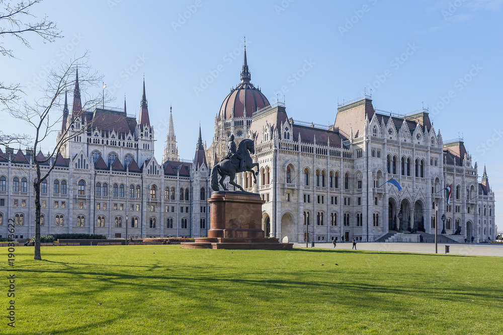 the beautiful Hungarian Parliament building on the background of green grass and blue sky