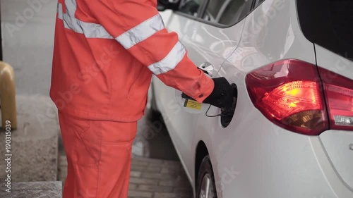 Gas Station Worker Refilling Car at Service Station. Clip. Male gas attendant fills the car photo