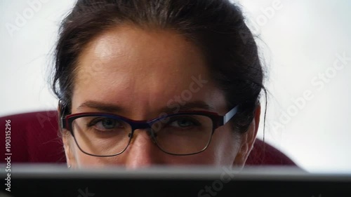 Close up of woman working in office at computer. Woman eye looking monitor, surfing Internet. Close up of the eye of a female researcher in front of a computer monitor. photo