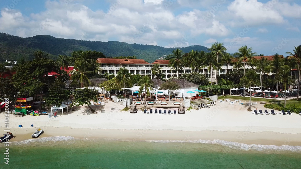 Top View of Paradise Beach. Beautiful tropical island with sand beach, palm trees. Aerial view of tropical beach on the island. Tropical landscape: beach with palm trees. Seascape: Ocean, sky, sea