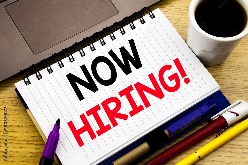 Now Hiring. Business concept for Hire Recruitment written on notebook book on the wooden background in the Office with laptop coffee Now Hiring. Business concept for Hire Recruitment written on notebook book on the wooden background in the Office with laptop coffee