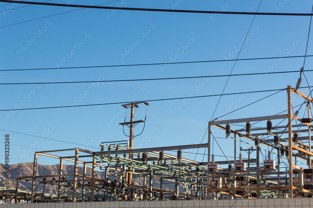 Electrical power transfer station against mountain range, blue sky, copy space, horizontal aspect Electrical power transfer station against mountain range, blue sky, copy space, horizontal aspect
