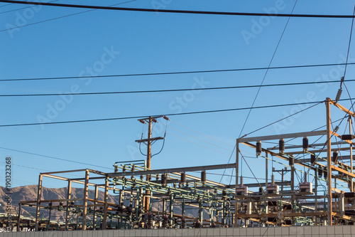 Electrical power transfer station against mountain range, blue sky, copy space, horizontal aspect